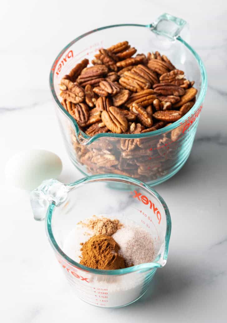 Ingredients you need: Large glass mixing pitcher with raw pecan halves. Another smaller glass pitcher has cinnamon, sugar, nutmeg, and salt.