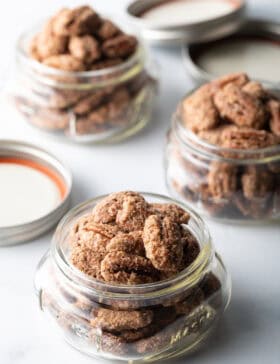 3 small glass jars overflowing with candied pecans.