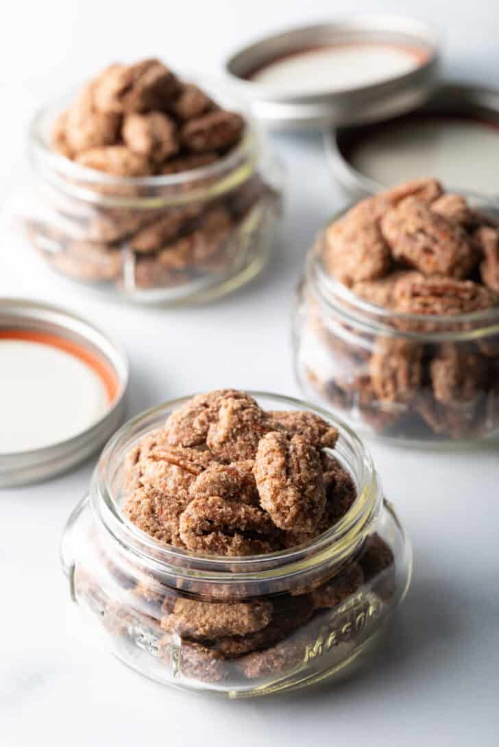 3 small glass jars overflowing with candied pecans.