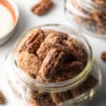 Close view of a glass jar overflowing with candied pecans.