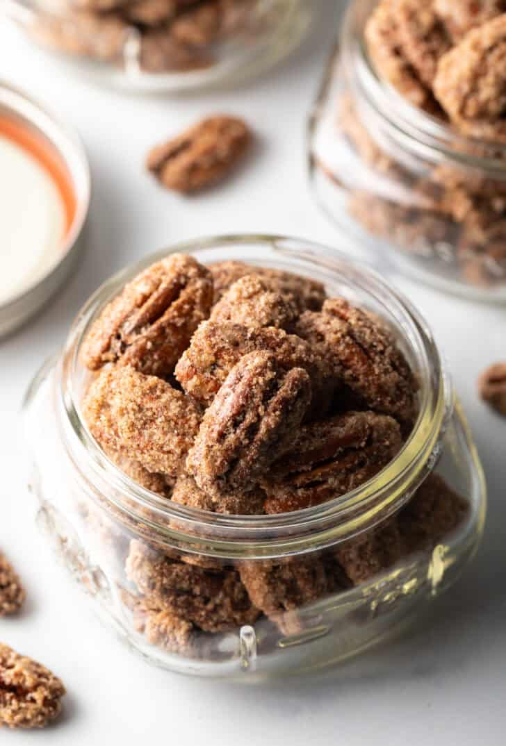 Close view of a glass jar overflowing with candied pecans.