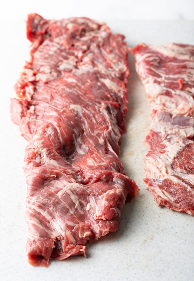 Raw skirt steak on white cutting board