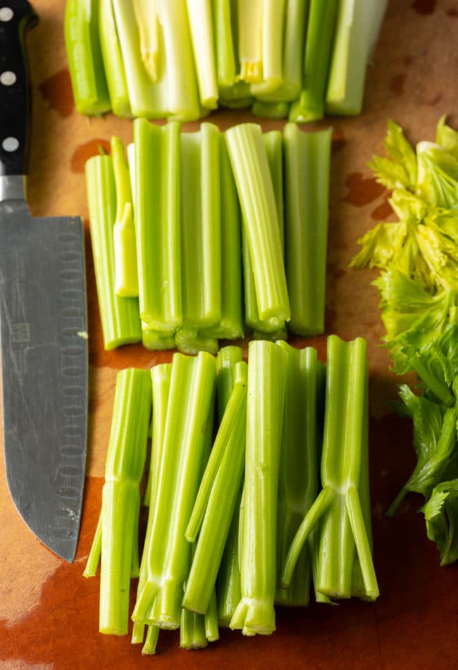 Celery being chopped on a cutting board. 