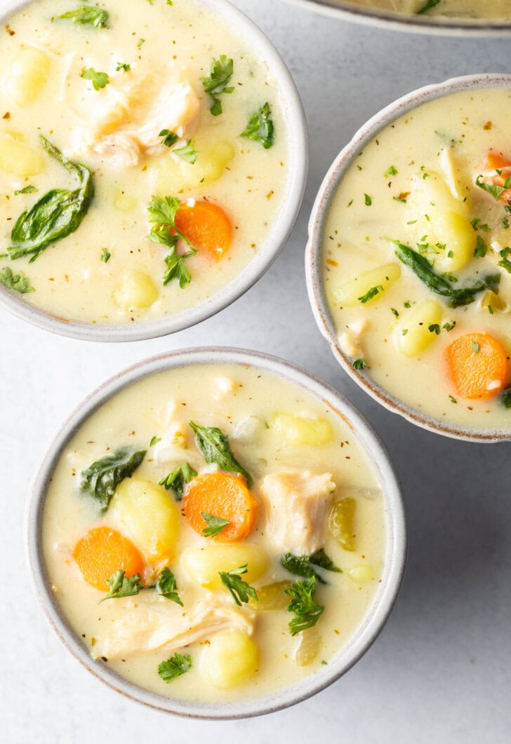 3 white bowls of chicken gnocchi soup.