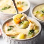 Bowlful of soup with a spoon holding a spoonful to camera.