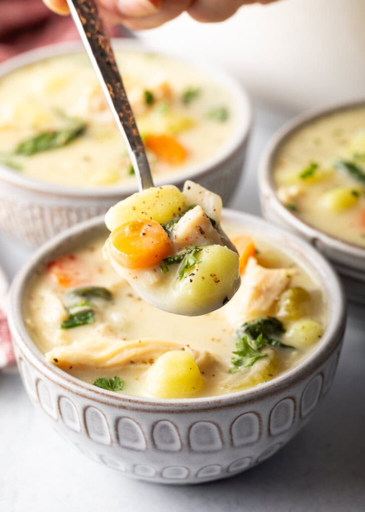 Bowlful of soup with a spoon holding a spoonful to camera.