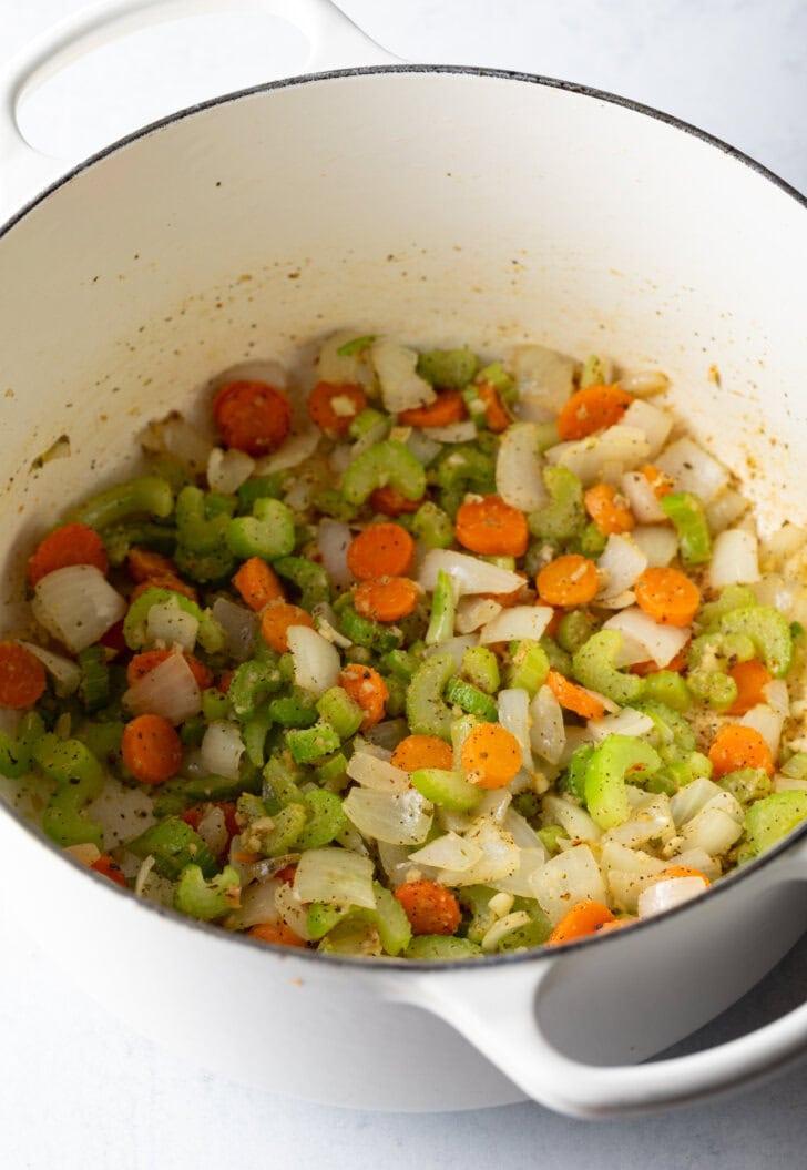 Chopped carrots, celery, and onion sautéing in a large pot.