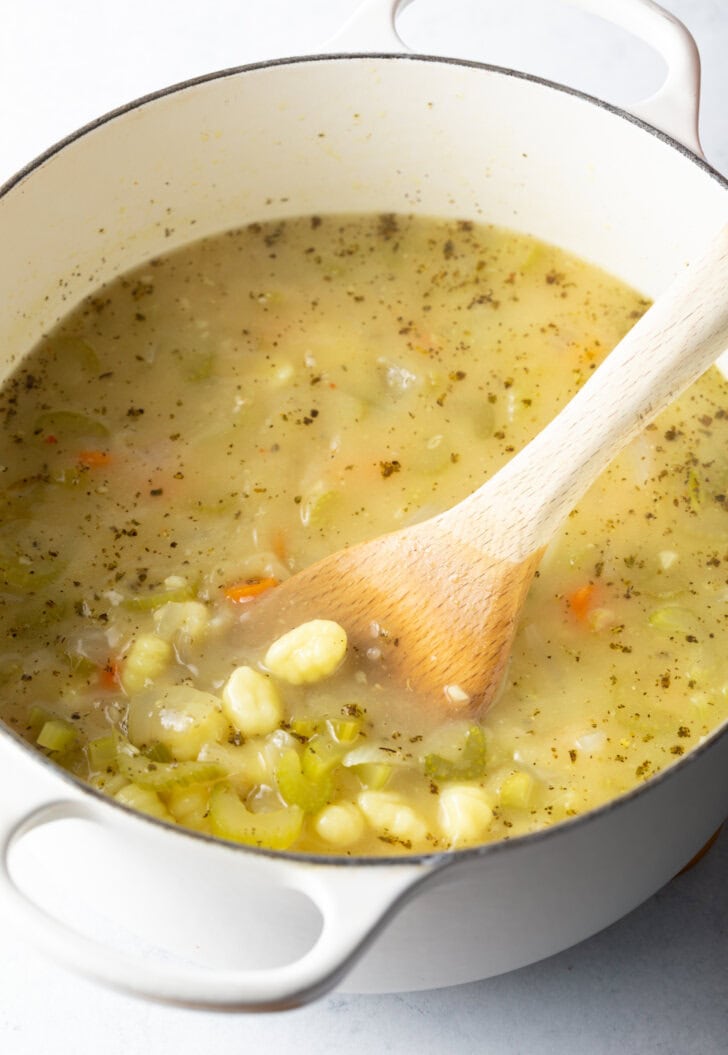 Stirring the soup broth with a wooden spoon.