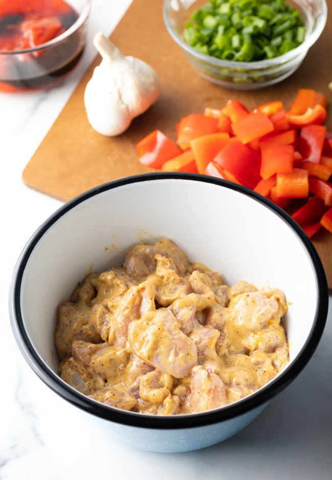 Marinated chicken pieces in a white bowl.