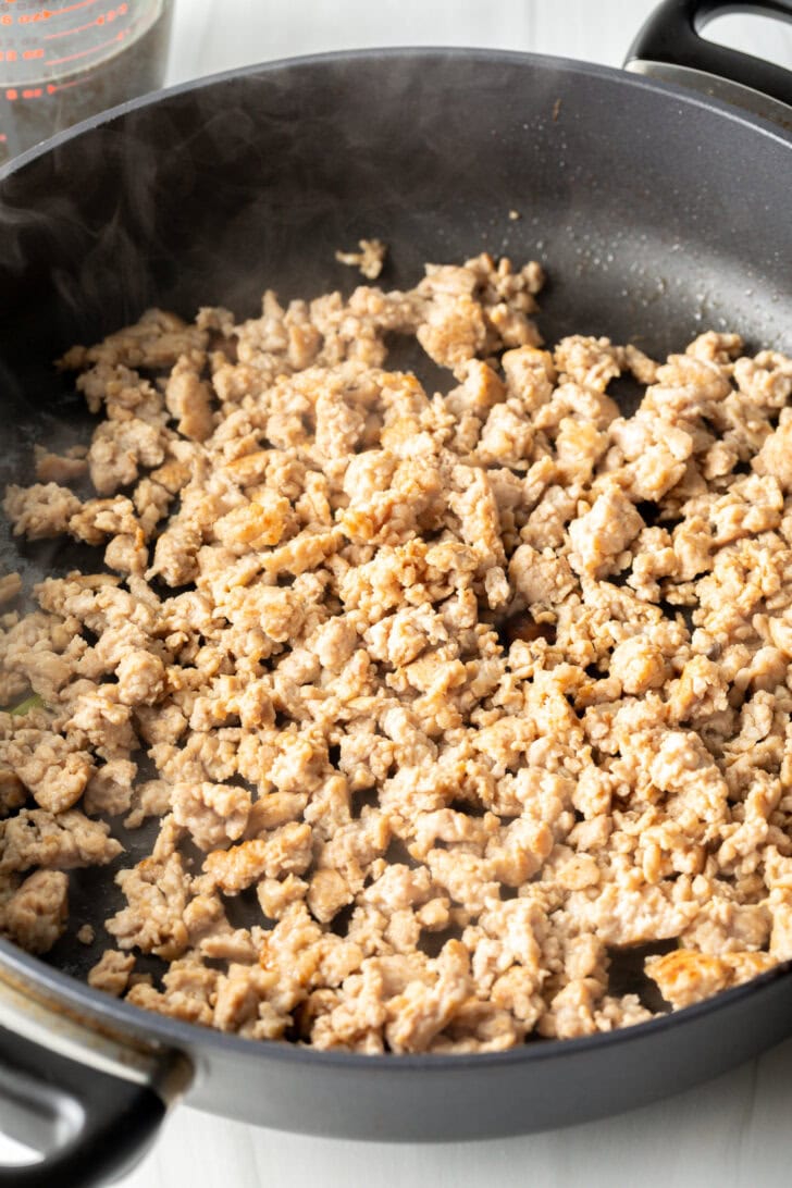 Cooking ground chicken in a large skillet.