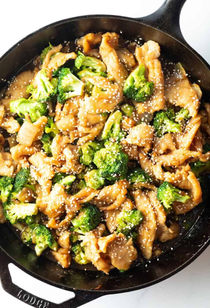 Top down chicken and broccoli in a large cast iron skillet.