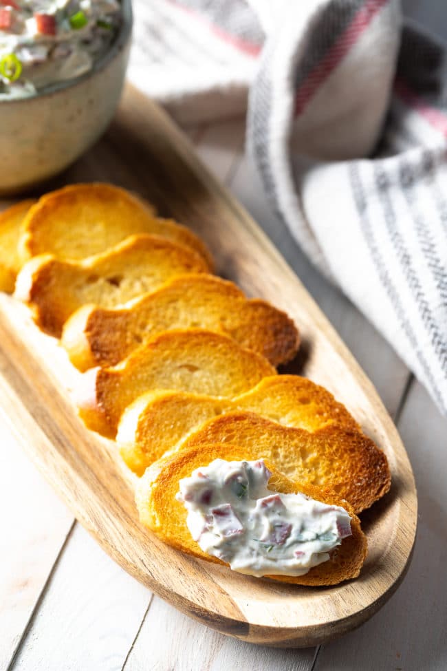 Pieces of toast lined up with the closes piece topped with chipped beef dip. 