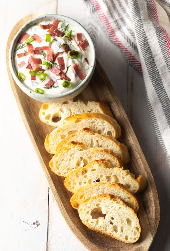 Dried beef dip in a small bowl with toasted bread next to it. 