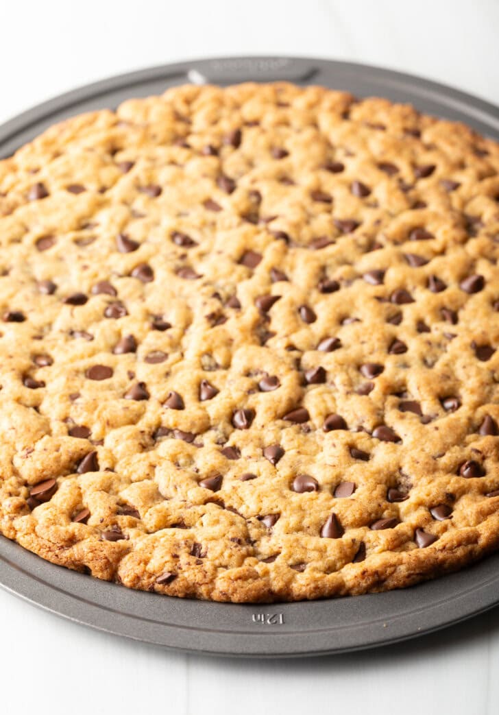 Large chocolate chip cookie cake baked in a pizza pan.