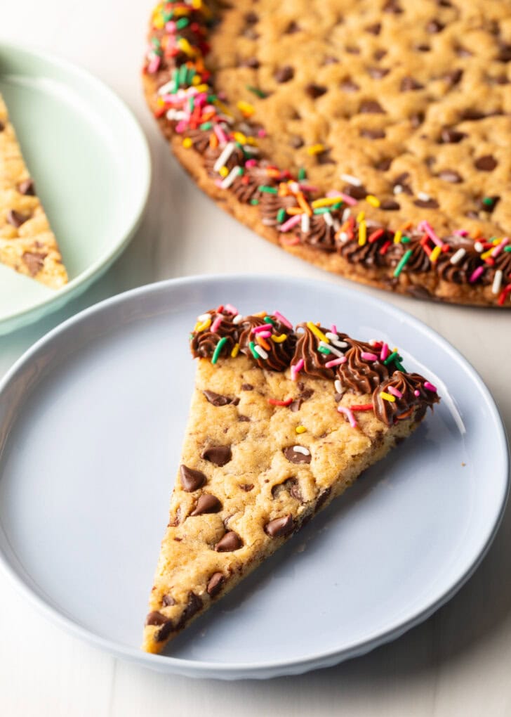 One triangle slice of homemade cookie cake on a pastel blue plate.