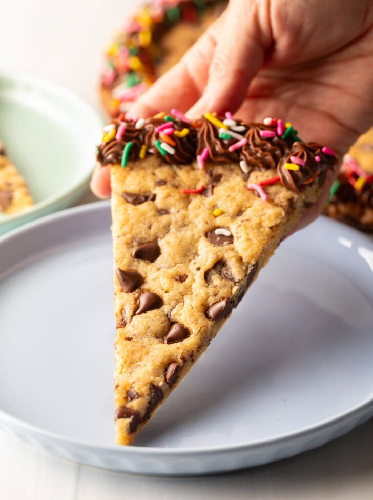 One triangle slice of homemade cookie cake on a pastel blue plate.