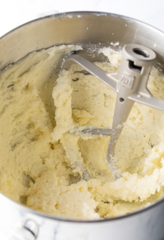 Creaming together butter and sugar in a metal mixing bowl.