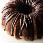 Top down view, circular chocolate sour cream bundt cake with a thick chocolate glaze drizzled on top.