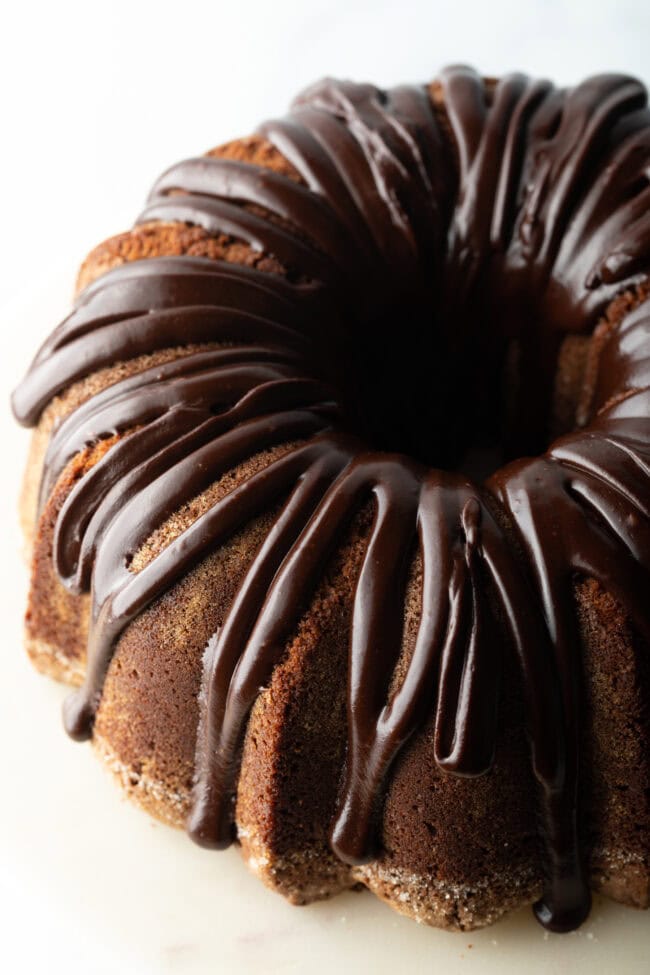 Top down view, circular chocolate sour cream bundt cake with a thick chocolate glaze drizzled on top.