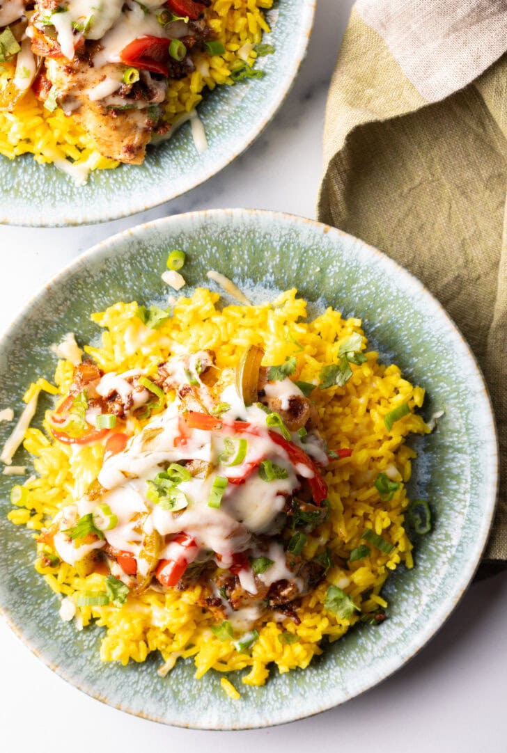 Chori pollo (chicken chorizo) covered in cheese on a bed of yellow rice.