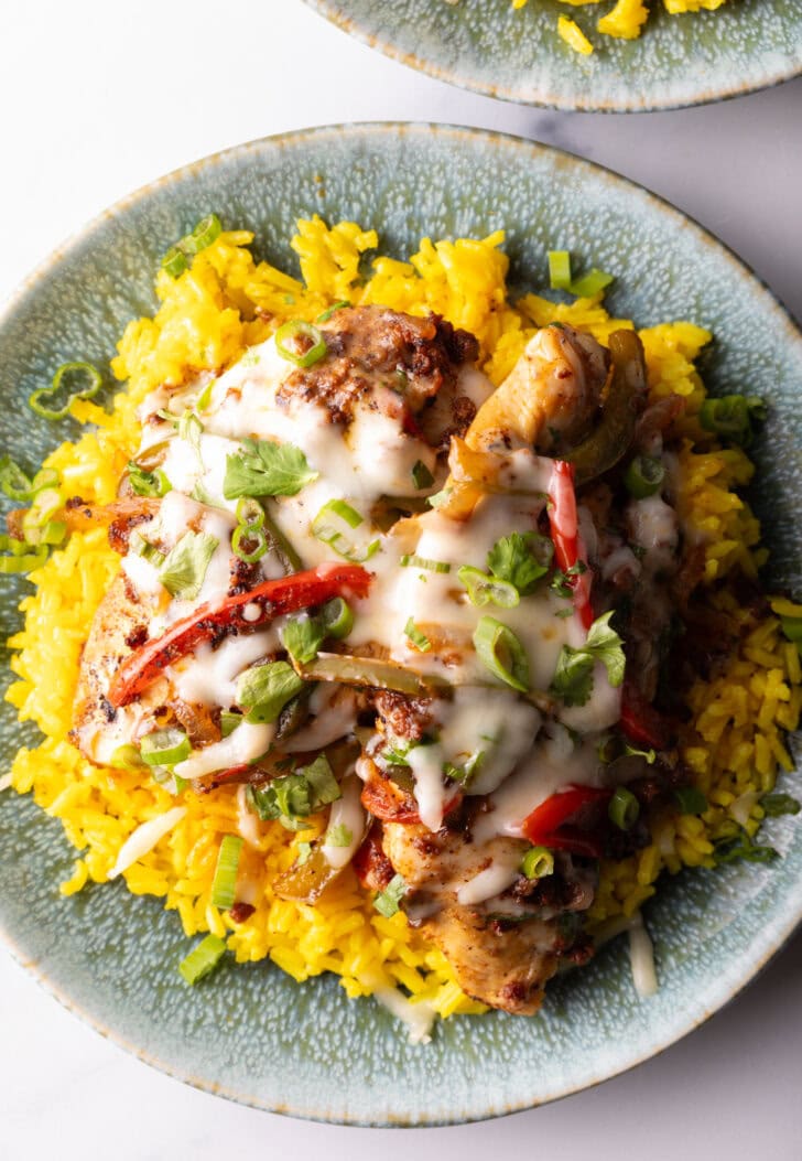 Chori pollo (chicken chorizo) covered in cheese on a bed of yellow rice.