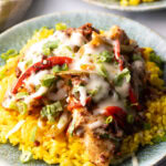 Chori pollo (chicken chorizo) covered in cheese on a bed of yellow rice.