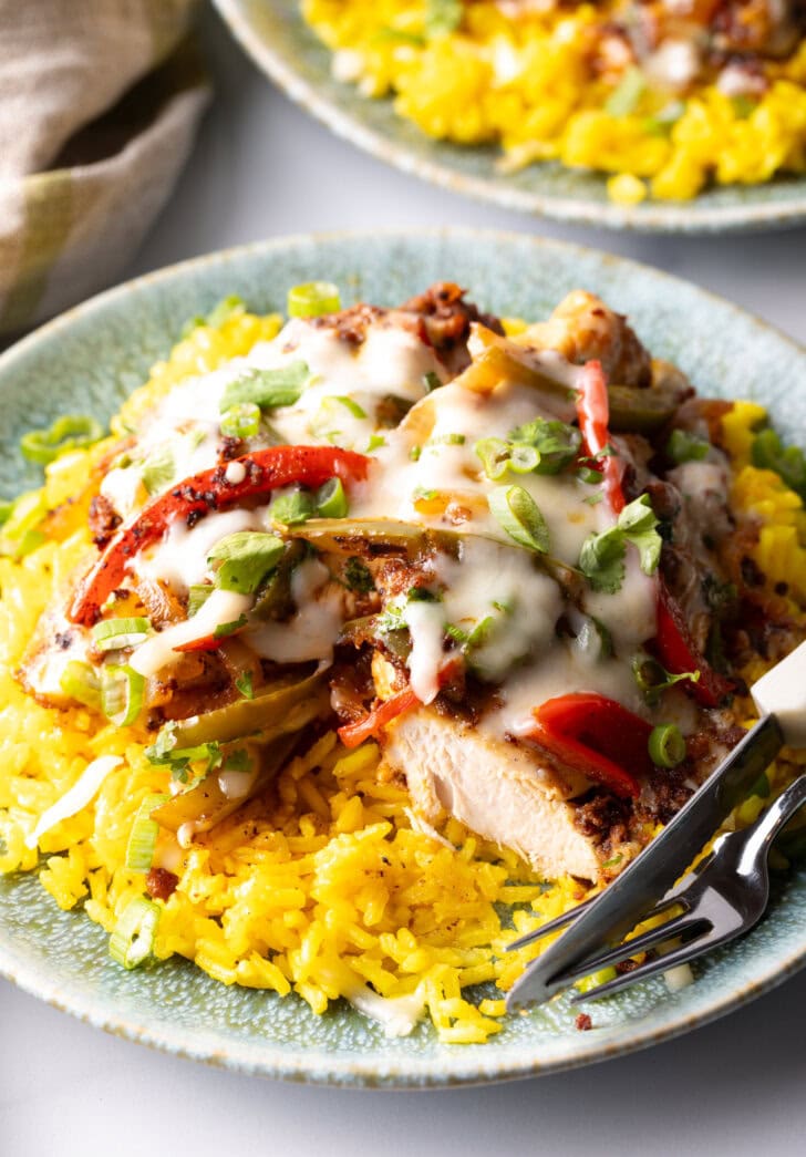 Chori pollo (chicken chorizo) covered in cheese on a bed of yellow rice.