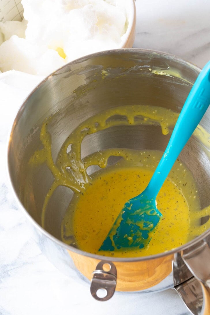 Whipped egg yolks with Italian seasoning in a stand mixer bowl. 