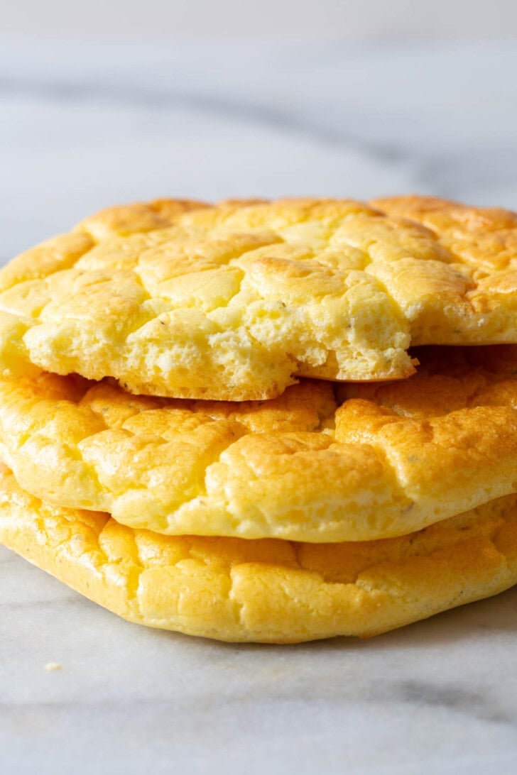 Pieces of cloud bread stacked on top of each other with one of them ripped in half to show the inside. 