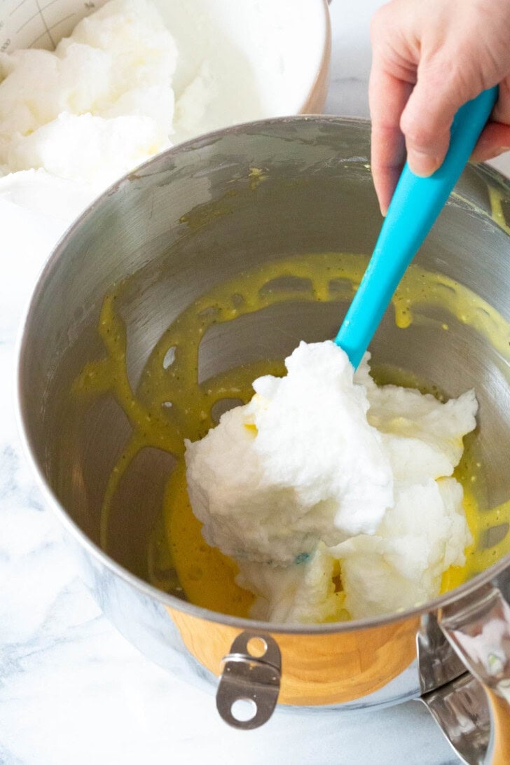 Whipped egg whites being folded into the egg yolk mixture. 