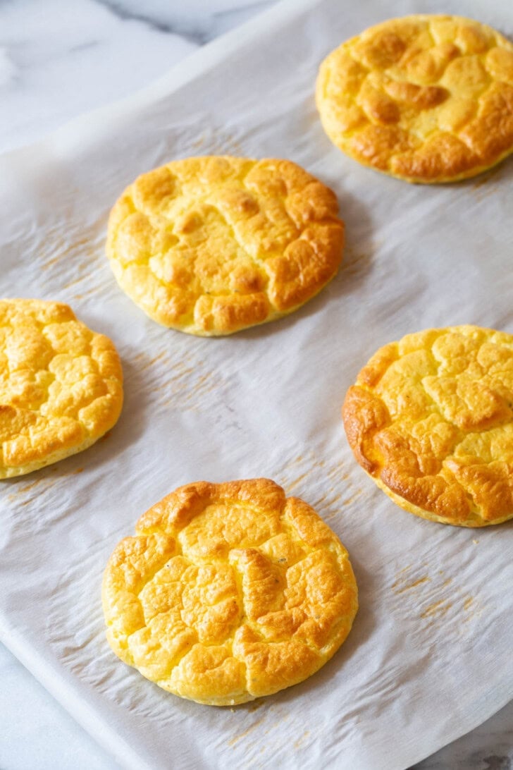 Cloud bread on a baking sheet lined with parchment paper after being baked. 