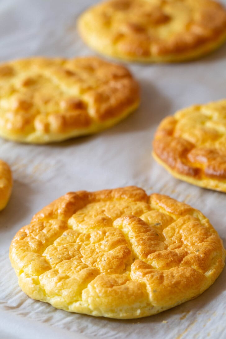 Piece of cloud bread on a baking sheet with more bread in the background. 