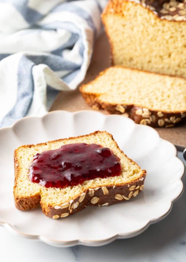 Slice of cottage cheese bread topped with red jelly, on a white plate.