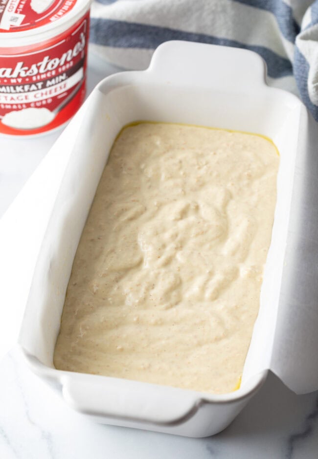 Bread batter in a white loaf pan.