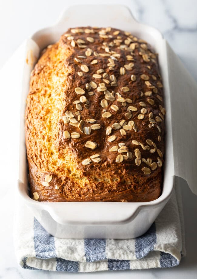 Full loaf of cottage cheese bread with oats in a white loaf pan.