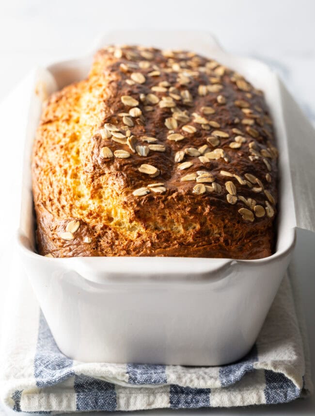 Full loaf of cottage cheese bread with oats in a white loaf pan.