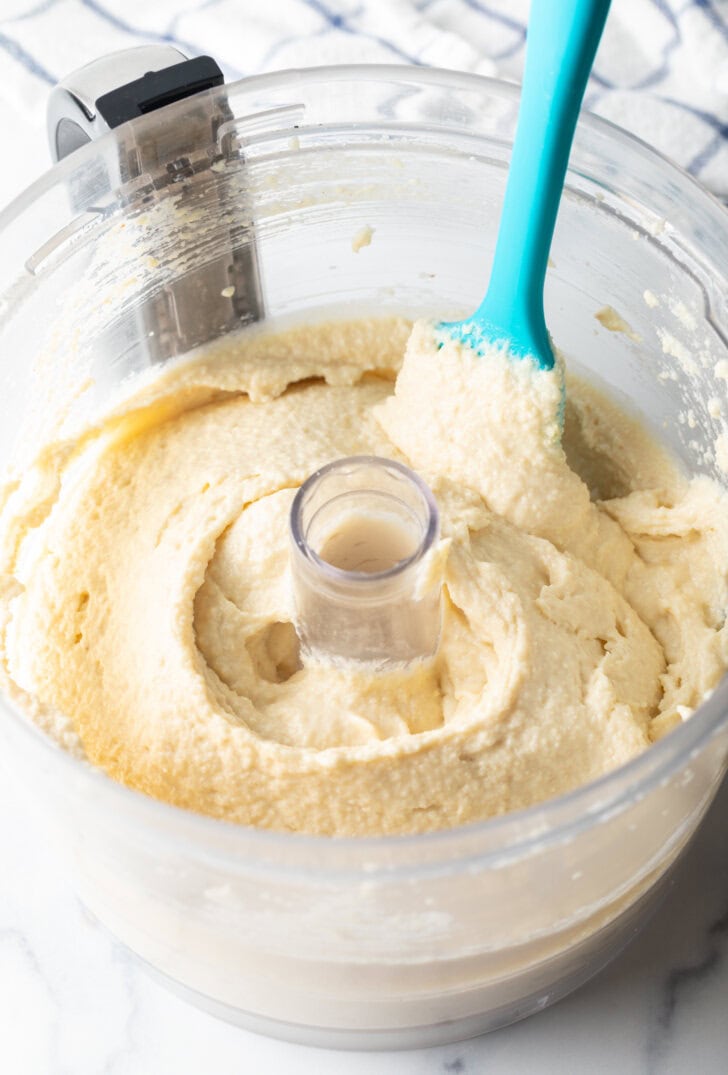 Blue spatula swishing cottage cheese cookie dough through a food processor.