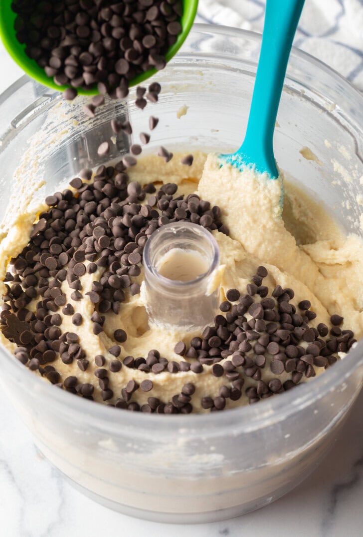 Adding chocolate chips to the food processor with cookie dough.