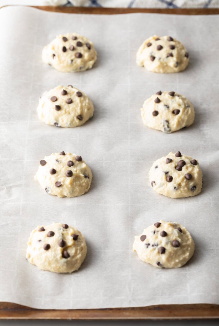 8 unbaked raw cottage cheese cookie dough cookies with chocolate chips on a baking tree.