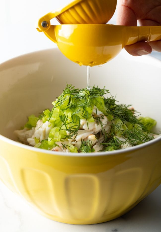 adding lemon juice, chopped celery and dill to a bowl