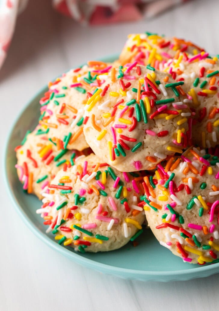 Blue plate piled with cookies covered in colorful sprinkles.