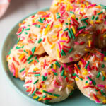 Blue plate piled with cookies covered in colorful sprinkles.