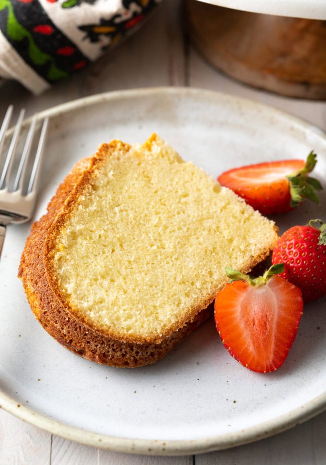 Side view of a single piece of this cream cheese cake with some fresh fruit 
