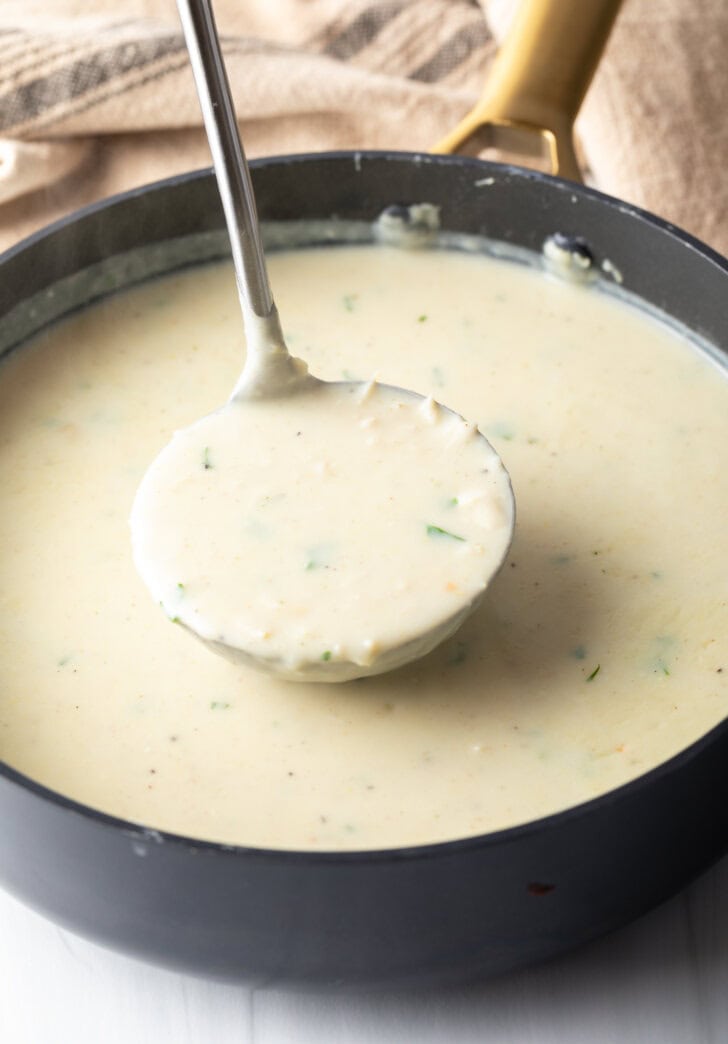 Large cooking post with soup being stirred by a metal ladle.