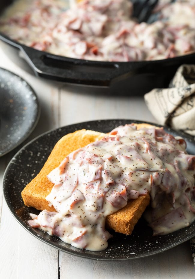 Creamed chipped beef on toast served on a black plate. 