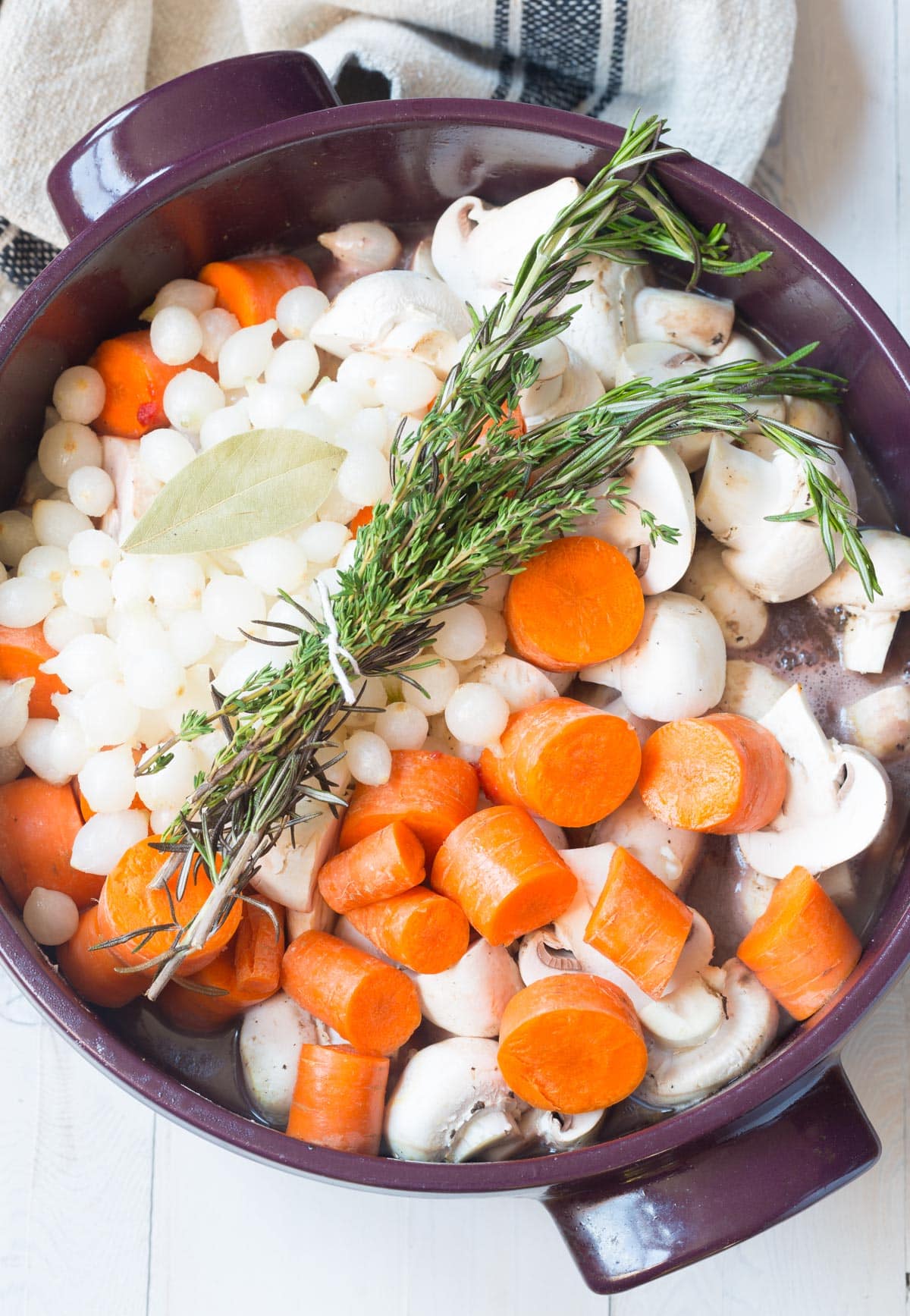 Raw Coq au Vin Recipe ingredients in pot with fresh herbs