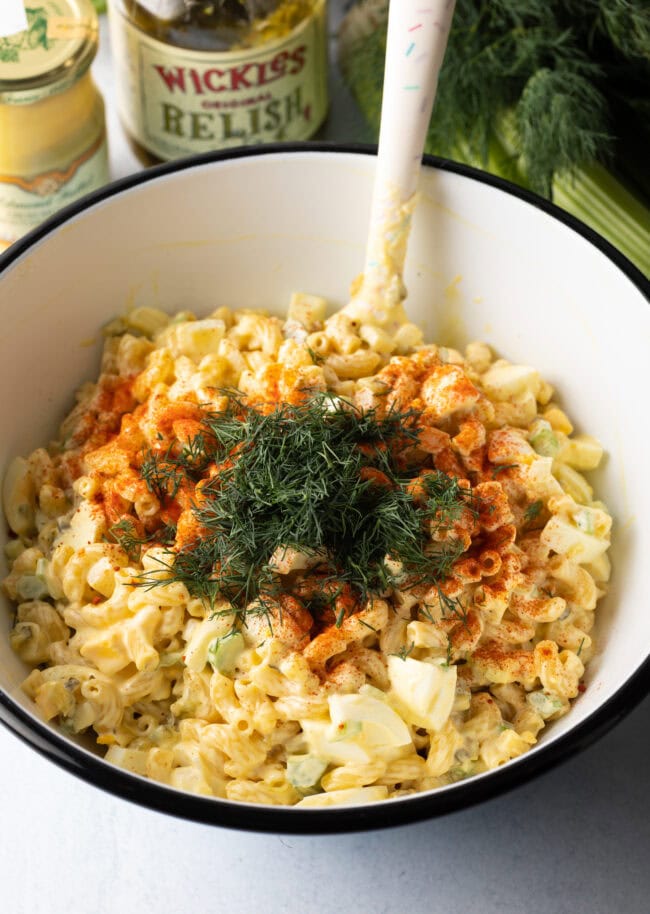 Adding fresh herbs to the bowl with noodles, eggs, and spices.