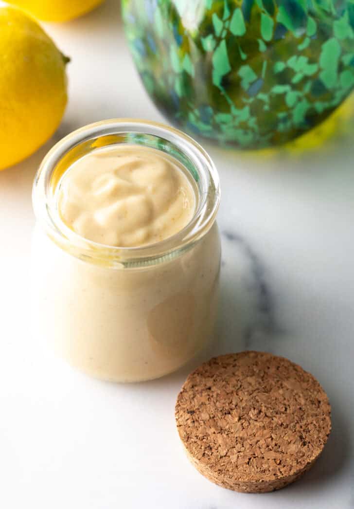 Top down view of a glass jar filled with rich creamy tahini dressing.