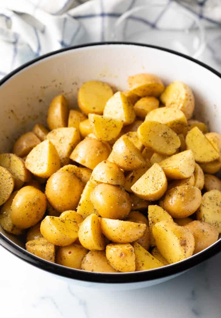 Large white bowl of halved yellow potatoes.