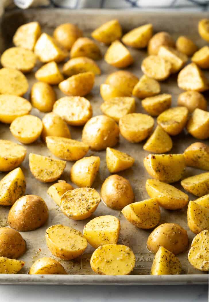 Raw halved yellow potatoes on a baking sheet.